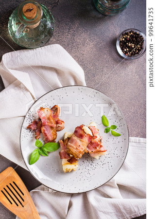 Rolls of fried bacon and mashed potatoes and basil on a plate on the table. Top and vertical view Rolls of fried bacon and mashed potatoes and basil on a plate on the table. Top and vertical view 99641735