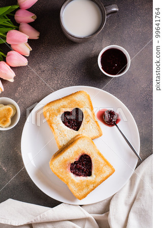 Toast with a heart filled with raspberry jam on a plate. Breakfast for a couple. Top and vertical Toast with a heart filled with raspberry jam on a plate. Breakfast for a couple. Top and vertical 99641764