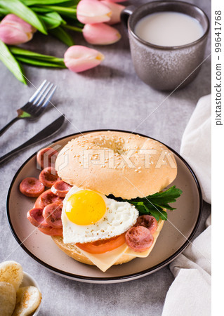 Fried egg heart, tomatoes, cheese and parsley in a bagel on a plate. Romantic breakfast. Fried egg heart, tomatoes, cheese and parsley in a bagel on a plate. Romantic breakfast. 99641768