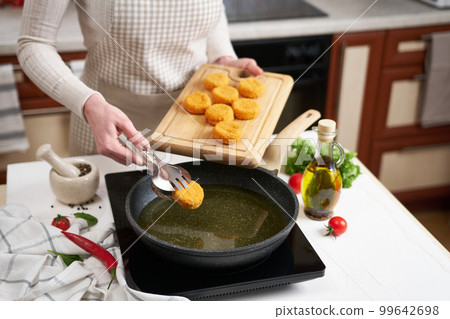 Woman puts cheese balls into frying pan with hot cooking oil Woman puts cheese balls into frying pan with hot cooking oil 99642698
