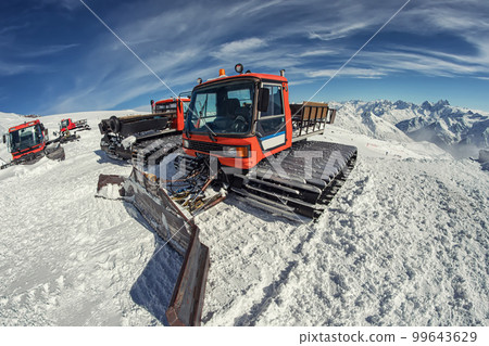 Snowcat stands in the highlands under the dazzling sunlight 99643629
