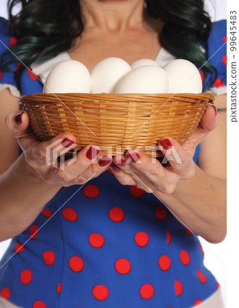 Woman in Retro Dress Holding Basket of Fresh Eggs 99645483