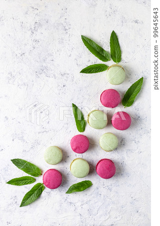 Design of green and pink macarons with mint leaves on white background. Traditional French sweet dessert. Design of green and pink macarons with mint leaves on white background. Traditional French sweet dessert. 99645643