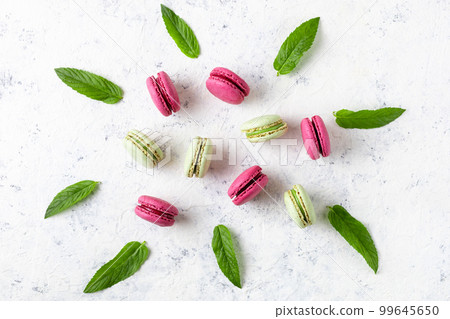 Design of green and pink macarons with mint leaves on white background. Traditional French sweet dessert. Design of green and pink macarons with mint leaves on white background. Traditional French sweet dessert. 99645650