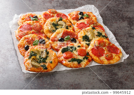 Hot assorted mini pizza or Pizzette with various toppings close-up on parchment. horizontal Hot assorted mini pizza or Pizzette with various toppings close-up on parchment. horizontal 99645912