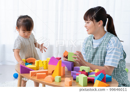 Child and nursery teacher playing with blocks 99646011