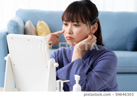檢查鏡子裡的皮膚麻煩的年輕女子 99646303