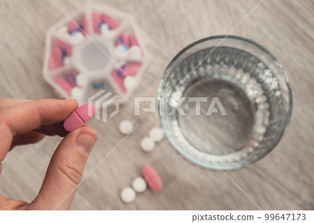 Woman sorting pills Organizer weekly shots Closeup of medical pill box with doses of tablets for daily take medicine with white pink drugs and capsules. Young woman getting her daily vitamins at home Woman sorting pills Organizer weekly shots Closeup of medical pill box with doses of tablets for daily take medicine with white pink drugs and capsules. Young woman getting her daily vitamins at home 99647173
