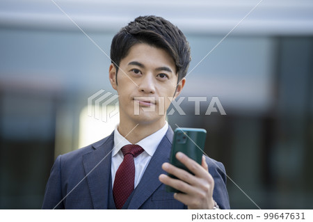 Businessman holding a smartphone looking at the camera portrait photography cooperation "LINK FOREST" 99647631