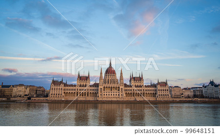 Panoramic view of Budapest Parliament from across Danube river, Hungary. Beautiful blue evening sky with pink clouds. Panoramic view of Budapest Parliament from across Danube river, Hungary. Beautiful blue evening sky with pink clouds. 99648151