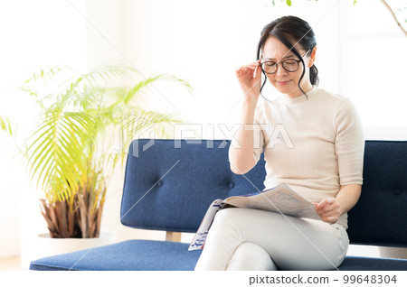 一位戴眼鏡的女士一邊看小冊子一邊思考 一位戴眼鏡的女士一邊看小冊子一邊思考 99648304