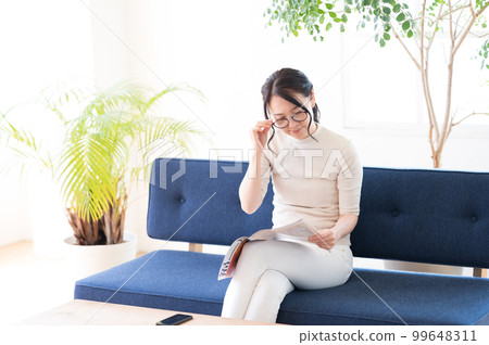 一位戴眼鏡的女士一邊看小冊子一邊思考 99648311