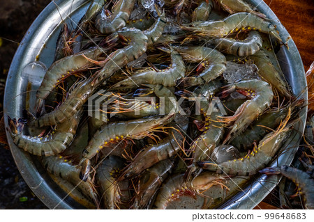 Raw whole shrimps for sale in a Fish market. Seafood Market with fresh caught prawns for sale. Heap of prawns on seafood market. Tropical marine crustaceans Raw whole shrimps for sale in a Fish market. Seafood Market with fresh caught prawns for sale. Heap of prawns on seafood market. Tropical marine crustaceans 99648683