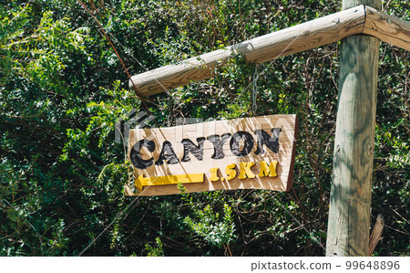 Directional sign post on a mountain footpath showing walking distance to the canyon. Ecological sign board 99648896