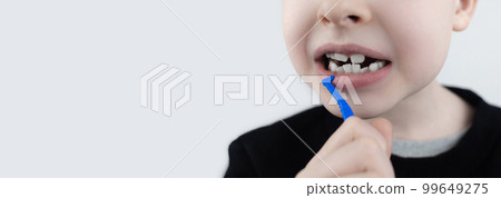 Interdental brush. A blond boy shows a brush for cleaning the interdental space. Brush for cleaning teeth and daily oral care. Dentistry and orthodontics 99649275