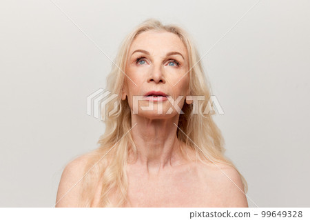 Portrait of beautiful middle-aged, mature woman with well-kept natural skin posing over grey studio background. Concept of natural beauty, face skin care, cosmetics 99649328