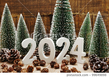 Happy New Year 2024 festive background with christmas tree and pine cone decoration on wooden background 99649898