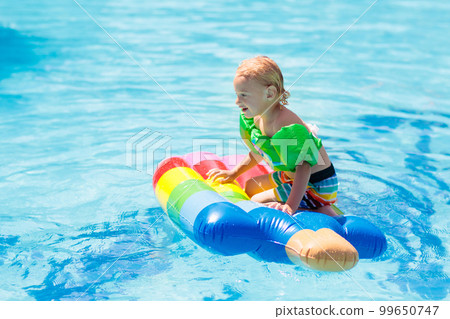 Kids on inflatable float in swimming pool. 99650747