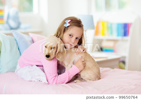 Child playing with dog. Kids play with puppy. 99650764
