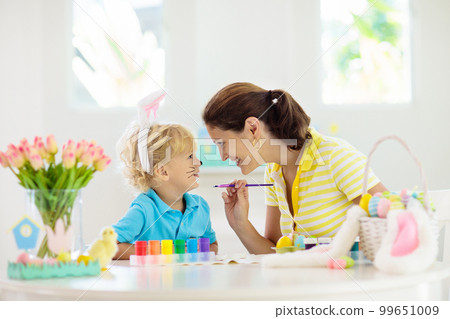 Mother and kids, family coloring Easter eggs. 99651009