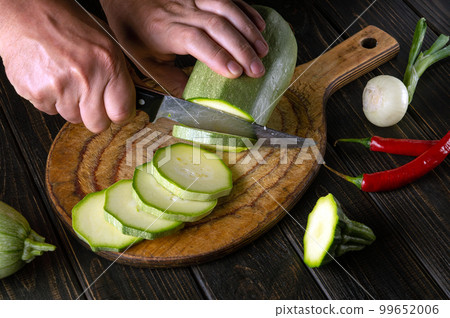 The chef cuts vegetable marrow into small pieces with a knife before preparing a delicious dinner. National food The chef cuts vegetable marrow into small pieces with a knife before preparing a delicious dinner. National food 99652006