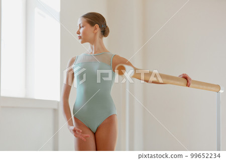 Beautiful teen girl, ballet dancer at dance school, standing at ballet barre, training on daytime with sunlight. Concept of classical ballet, art, choreography Beautiful teen girl, ballet dancer at dance school, standing at ballet barre, training on daytime with sunlight. Concept of classical ballet, art, choreography 99652234