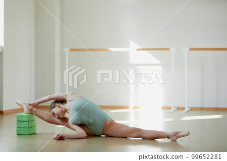 Professional performer. Tender teen girl, ballerina training in ballet school on daytime. Stretching exercises, sitting on twine. Concept of classical ballet, art, choreography Professional performer. Tender teen girl, ballerina training in ballet school on daytime. Stretching exercises, sitting on twine. Concept of classical ballet, art, choreography 99652281