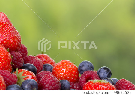 Pile od strawberries, blueberries, raspberries on green background 99653523