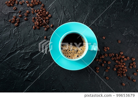 Coffee cup, shot from the top on a black slate background with coffee beans Coffee cup, shot from the top on a black slate background with coffee beans 99653679