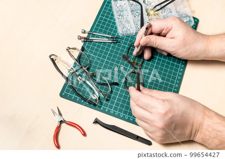 technician replaces eyeglass nose pads close up 99654427