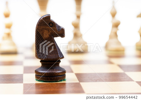 black knight against white chess pieces on board black knight against white chess pieces on board 99654442