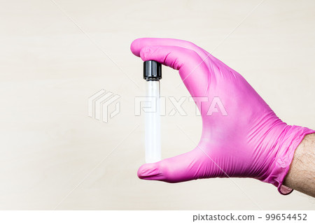 gloved hand holds closed test-tube over desk gloved hand holds closed test-tube over desk 99654452