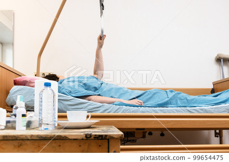 tabe and hospital bed with woman holding handle 99654475