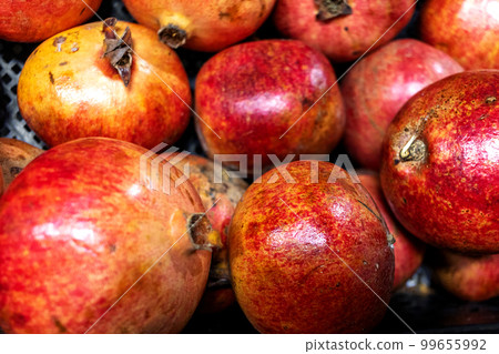 Ripe pomegranates in natural form without processing with defects and imperfections on the market counter close-up Ripe pomegranates in natural form without processing with defects and imperfections on the market counter close-up 99655992