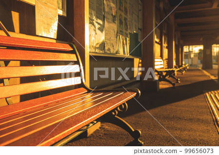 A station bench dyed in the orange sun 99656073