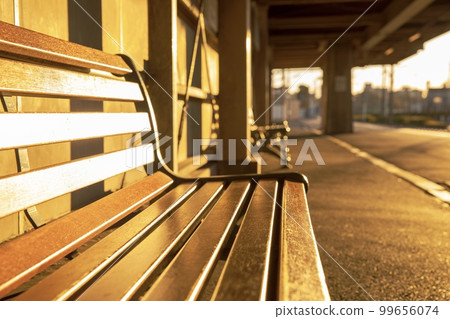 A station bench dyed in the orange sun 99656074