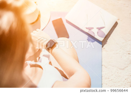 Digital nomad, Business woman working on laptop by the sea. Pretty lady typing on computer by the sea at sunset, makes a business transaction online from a distance. Freelance, remote work on vacation 99656644