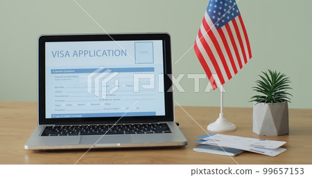 Online United States of American Visa Application showing on a laptop computer screen sitting on a desk. Travelling abroad or immigration concept. 99657153