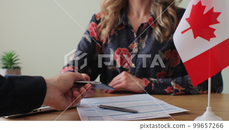 Canadian woman consular officer giving passport to male immigrant, work visa, citizenship. Visa Application online form immigration concept. Visa approval. Canadian woman consular officer giving passport to male immigrant, work visa, citizenship. Visa Application online form immigration concept. Visa approval. 99657266