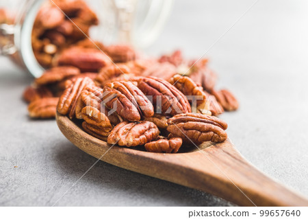 Peeled pecan nuts in wooden spoon. 99657640