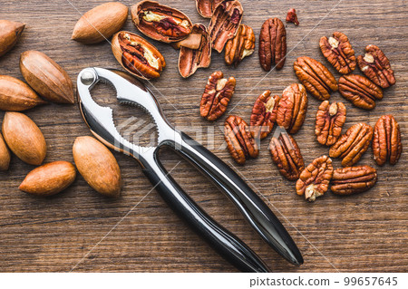 Peeled pecan nuts and nutcracker on wooden table. Top view. 99657645