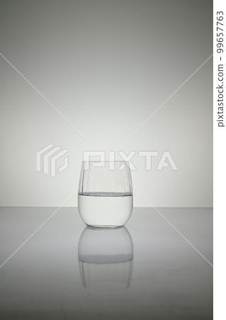 Vertical shot of water glass isolated on a white shiny surface Vertical shot of water glass isolated on a white shiny surface 99657763