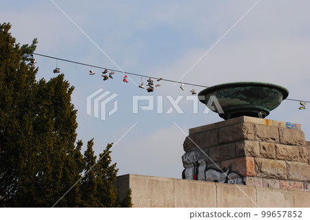 Low-angle shot of shoes hanging on a rope leash with a cloudscape in the background 99657852