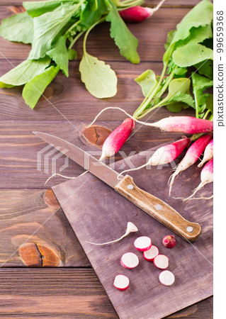 Fresh ripe radish cut into pieces on a cutting board and kitchen knife on a wooden table 99659368