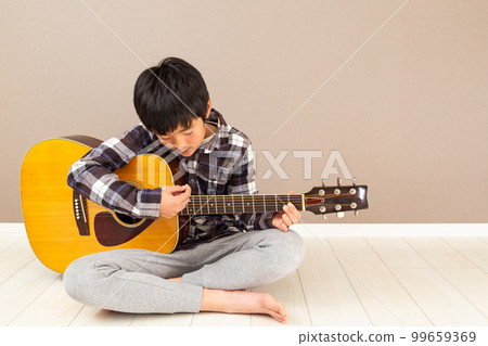 A boy playing a guitar 99659369