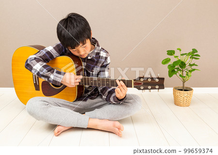 A boy playing a guitar A boy playing a guitar 99659374