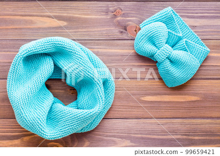 Knitted mint snud and headband on a wooden background. Top view 99659421