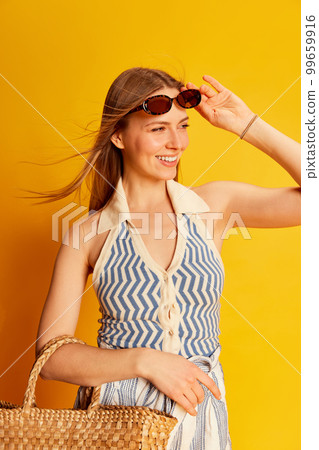 Young beautiful smiling woman with long blonde hair in summer style clothes posing over bright yellow background. Happiness, emotions concept Young beautiful smiling woman with long blonde hair in summer style clothes posing over bright yellow background. Happiness, emotions concept 99659916