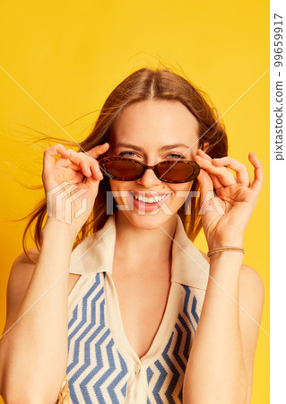 Portrait of excited happy young beautiful woman with long blonde hair in summer style clothes posing over bright yellow background. Happiness, emotions concept Portrait of excited happy young beautiful woman with long blonde hair in summer style clothes posing over bright yellow background. Happiness, emotions concept 99659917