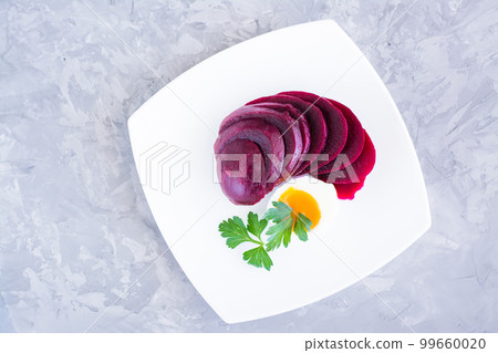 Cooked beetroot chopped and boiled chicken egg with parsley on a plate. Top view Cooked beetroot chopped and boiled chicken egg with parsley on a plate. Top view 99660020